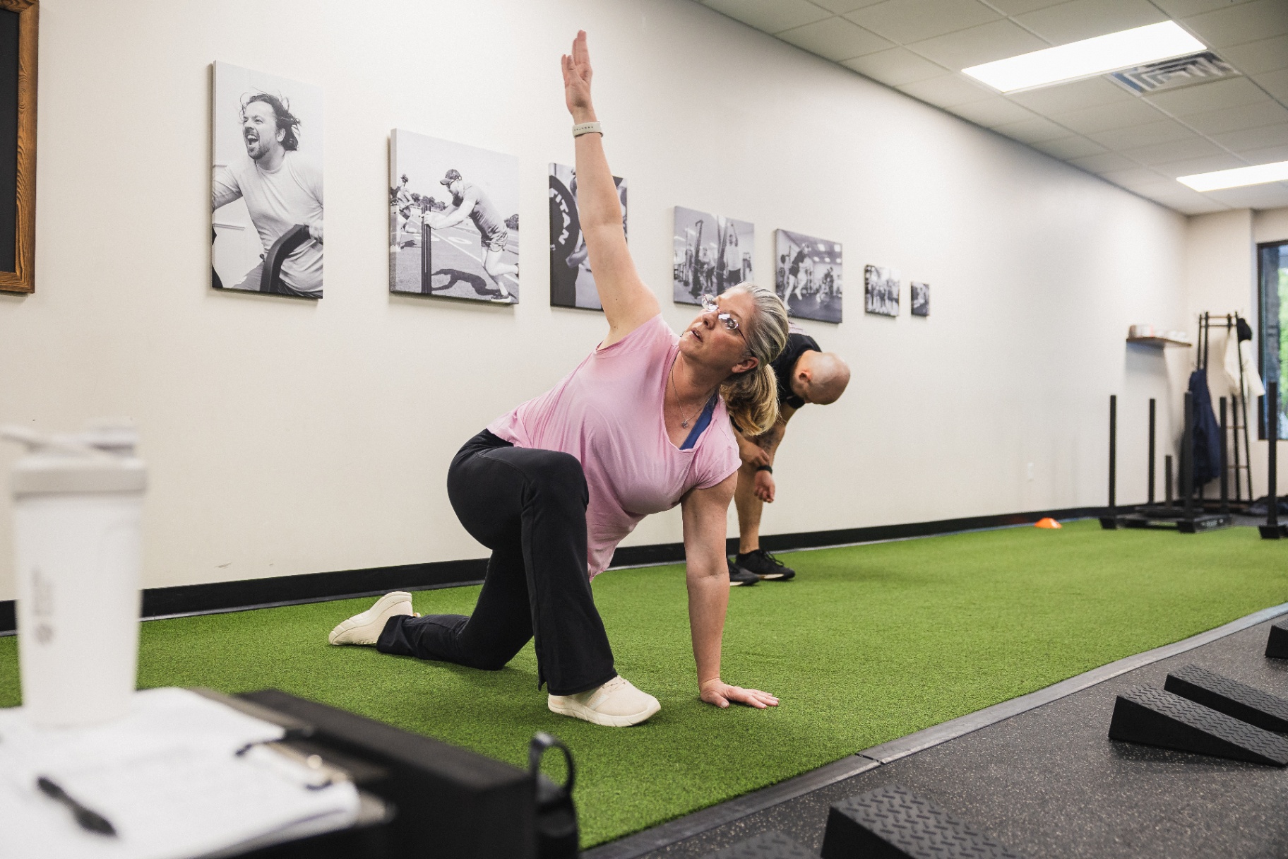 Adult client doing a mobility stretch on the turf