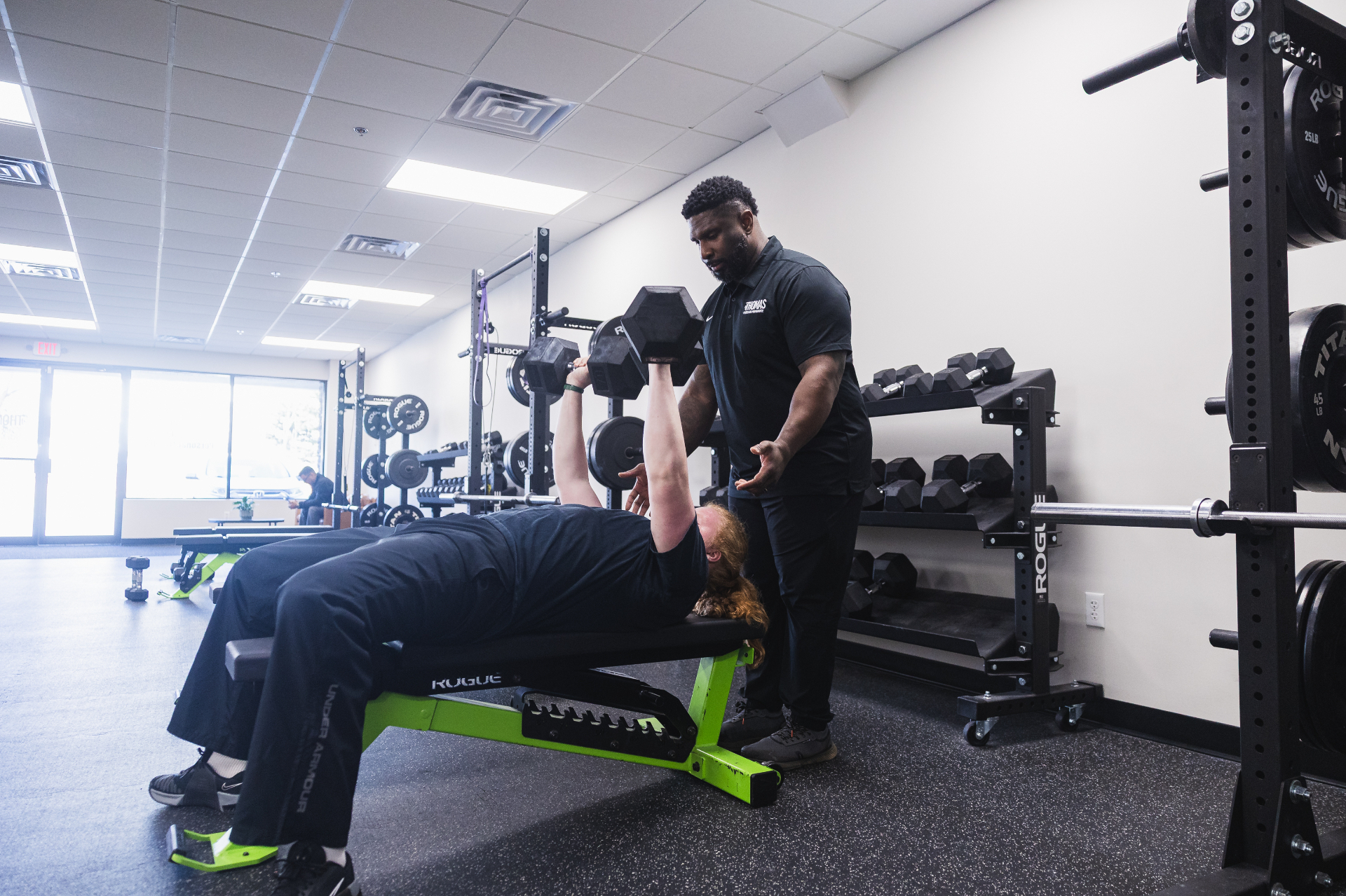 Adult client bench pressing with coach spotting