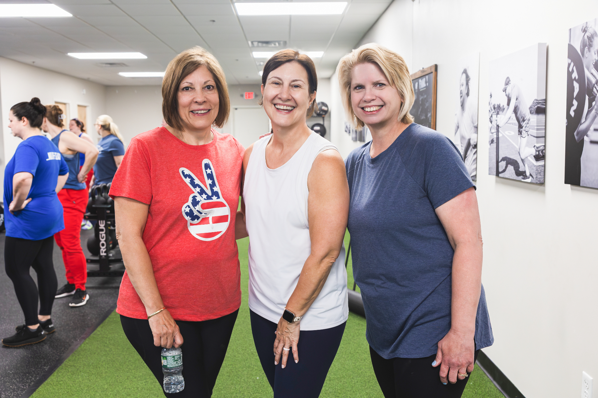 Three adult members smiling together after a workout